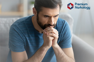 Мужчина сидит на диване и думает